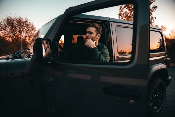 Man in thought in car with door open